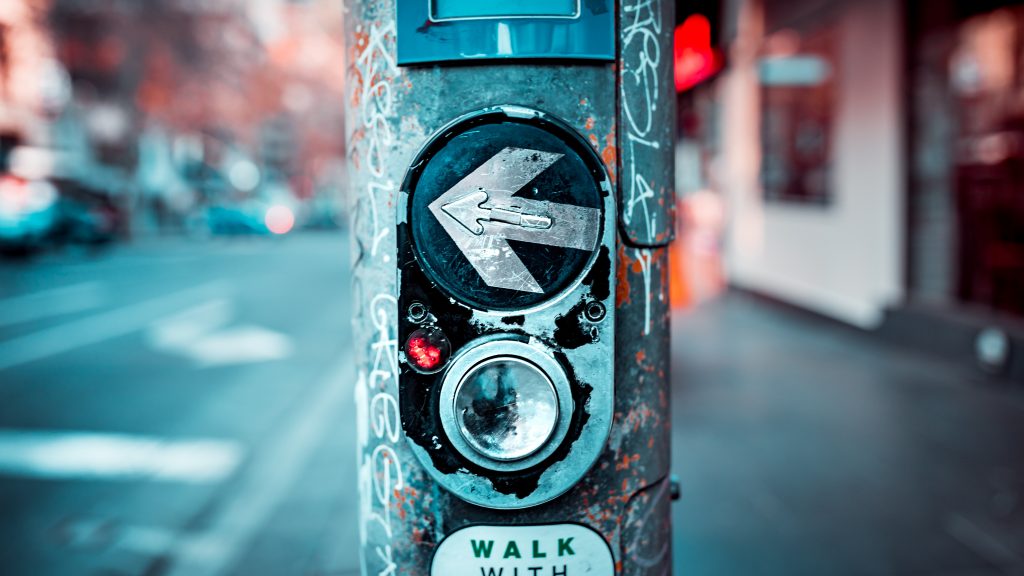 Picture of a pedestrian walking button in urban Melbourne pointing left on a