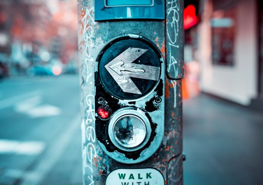 Picture of a pedestrian walking button in urban Melbourne pointing left on a