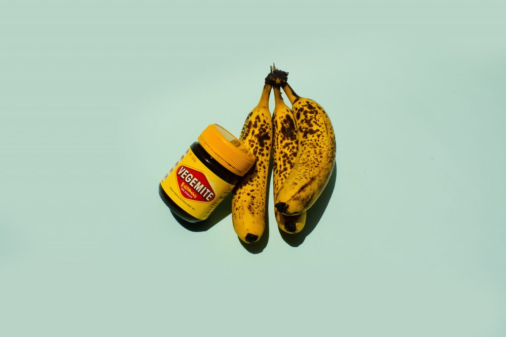 Picture of vegemite and bananas on a green background