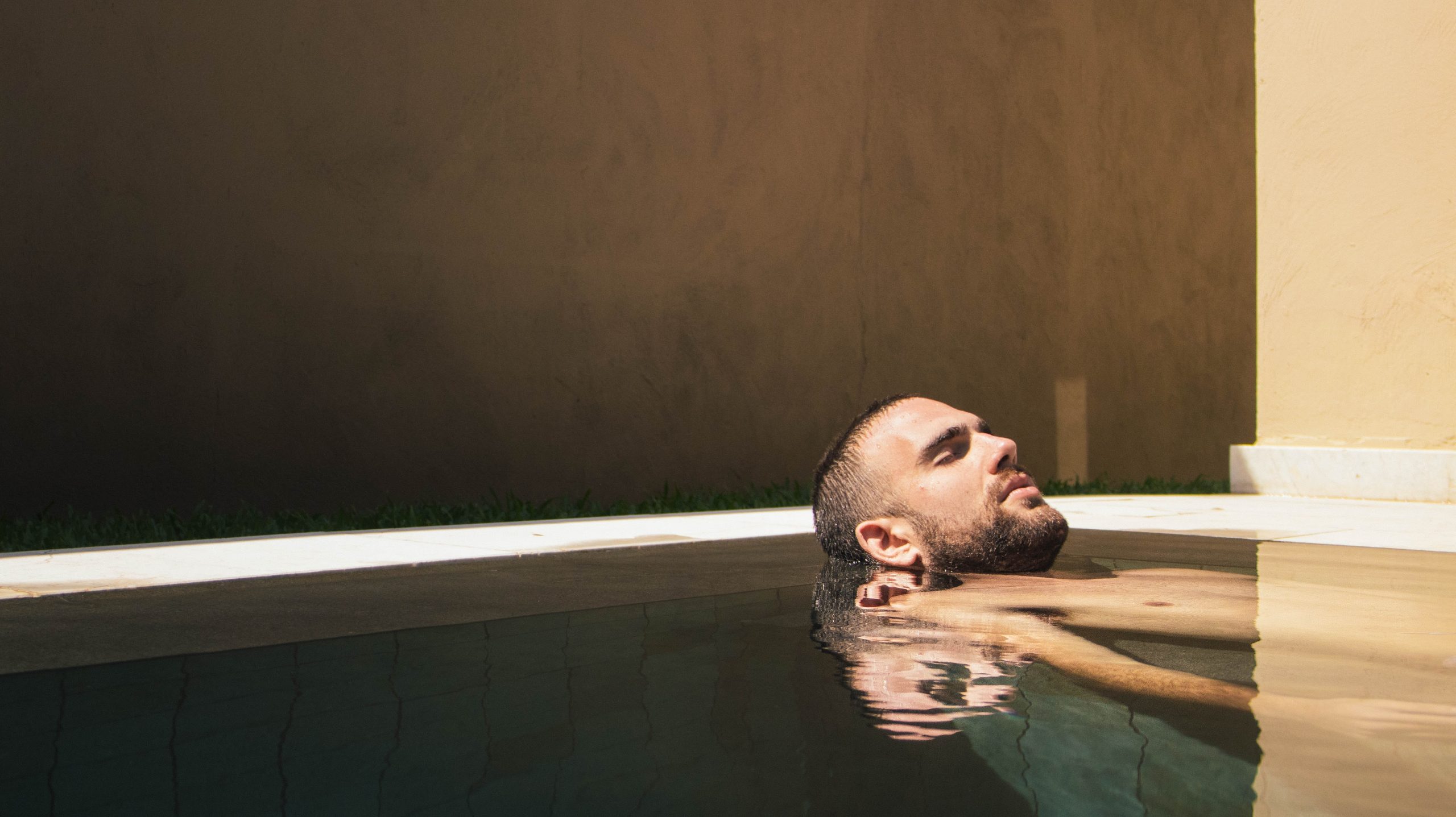 Man relaxing in a bath, with the water still and soft lighting. He is enjoying a spa package for men