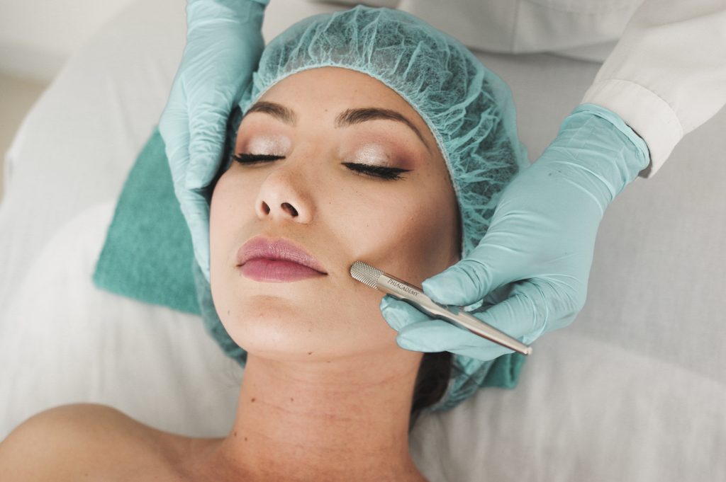 A woman is lying with a surgical mask on and she is having a microdermabrasion Melbourne treatmentCBD with a diamond-tipped pen