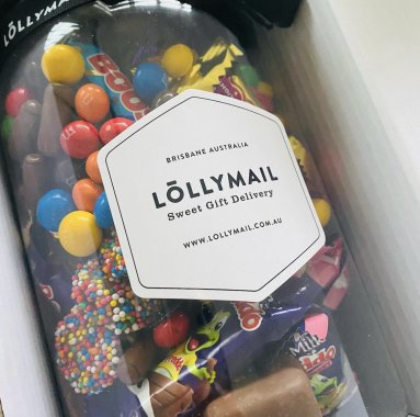 Picture of a jar filled with chocolates and chocolate bars, with a sticker that says LOLLYMAIL