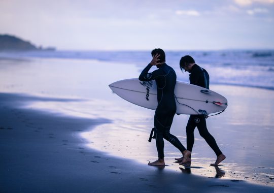 Picture of two surfers walking out from the ocean holding surf boards in Torquay Victoria