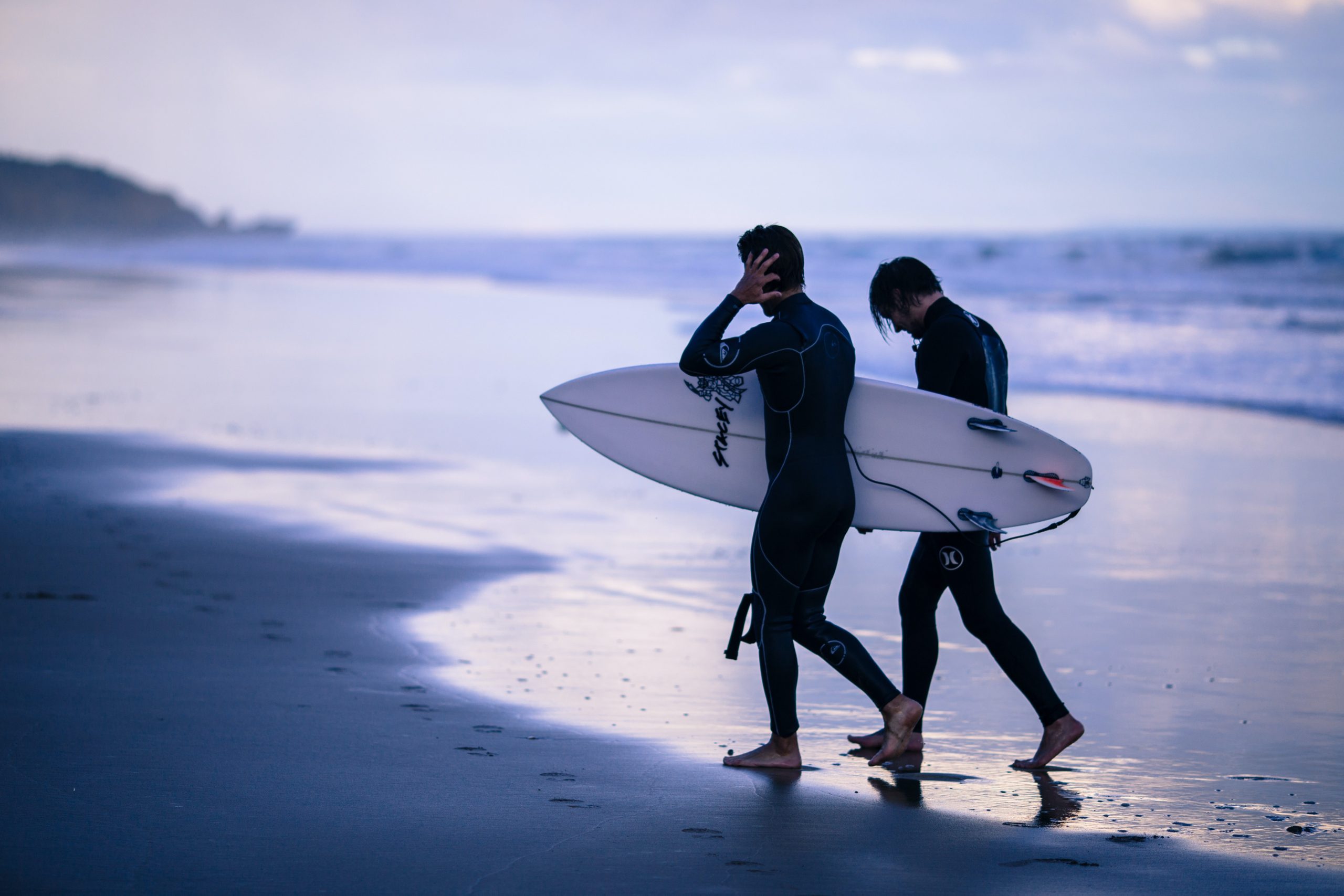 Picture of two surfers walking out from the ocean holding surf boards in Torquay Victoria