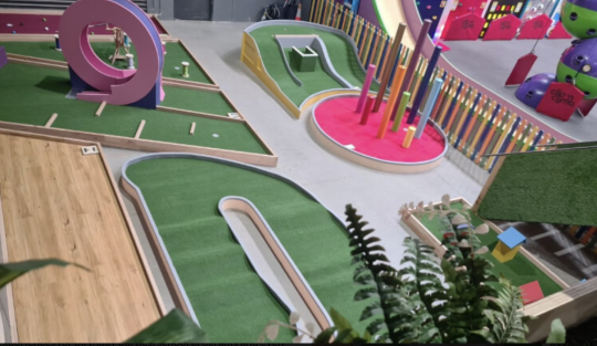 Picture of the Go Climb Coburg mini golf course in Melbourne, with green grass snaking through the open area and bright attractions throughout