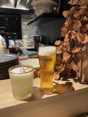 Picture of a Japanese cocktail and a Suntory beer at Yakikami South Yarra, with the drinks perched on a bench next to the grill