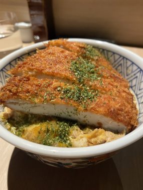 Picture of the Katsu Don from Yakikami South Yarra, with green garnish on top of the crumbed pork and egg and rice below the protein in a blue bowl