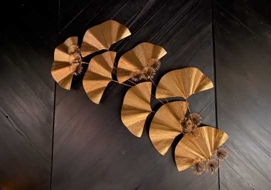 Picture of the chic decor at Yakikami South Yarra. The picture shows a copper flower detail on a wooden wall