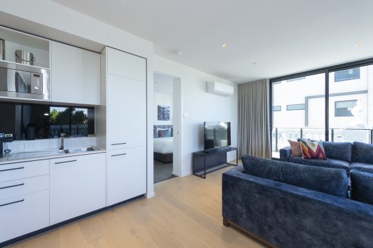 Picture of the kitchen and living space in the two bedroom apartments at R Hotel Geelong accommodation, with a glimpse to one of the bedrooms through the hallway