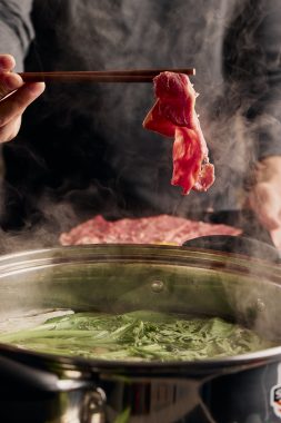 Picture of meat being held with chopsticks above a pot of soup, with this hot pot one of the key menu items at Cambodia's Kitchen