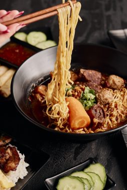 Picture of noodle soup with the noodles held above the bowl with chopsticks, an authentic dish at Cambodia's Kitchen