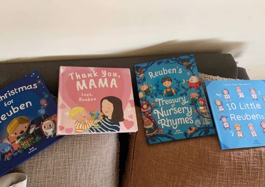 The picture of four Wonderbly books on a couch. There is a personalised Christmas book, a Mother's Day personalised book, a nursery rhyme book and a counting book from Wonderbly books