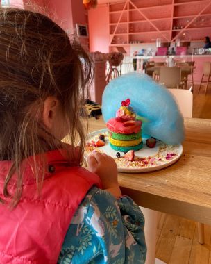 Picture of a little girl sitting in front of Rainbow Pancakes at Feekah Cafe Moonee Ponds