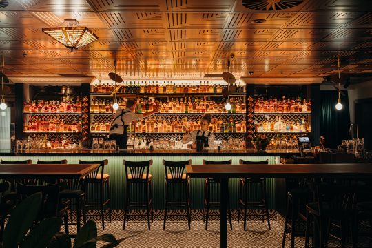 Picture of Nick & Nora's Melbourne bar, with the alcohol back-lit and two bartenders making drinks