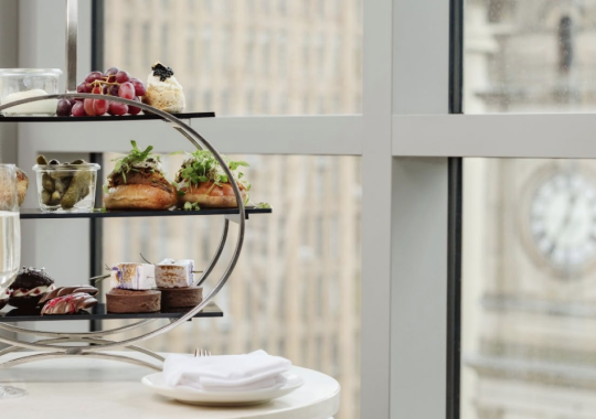 Picture of a high tea stand with a glass of champagne in front of a window at The Westin Melbourne