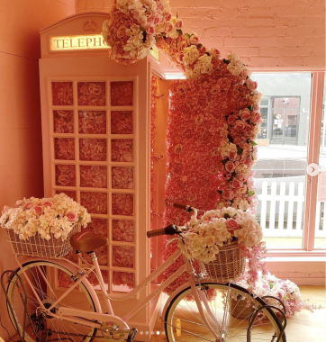 Picture of a London phone box with roses and flowers encrusting the exterior, with a pink bike next to the phone box at Feekah cafe Melbourne