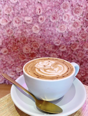 Picture of a latte in front of a rose-lined wall at Feekah cafe Moonee Ponds