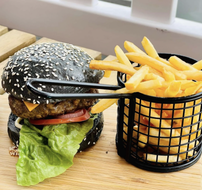 Picture of a black bun Chicken Burger at Feekah cafe Moonee Ponds, next to a basket of french fries