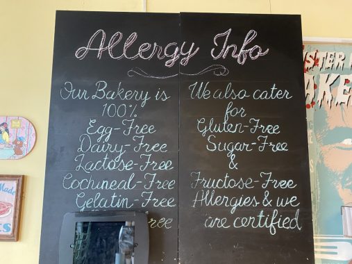 Picture of the blackboard at Mister Nice Guy's Bakeshop that outlines the allergy information for each item sold at the bakery.