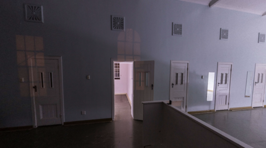 Picture of one of the most haunted places in Melbourne, the Arandale Mental Hospital. The image shows five white doors and blue walls, with one of the doors wide open