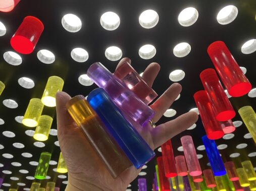 Chaos Lab Melbourne picture that shows a hand holding the plastic colour cylinders that can be used to make colourful pieces of art on the walls.