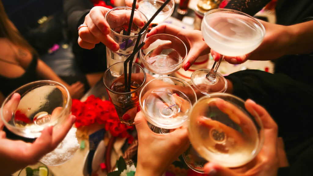 Picture of clinking glasses with alcohol and toasting, celebrating the fun things to do in Melbourne