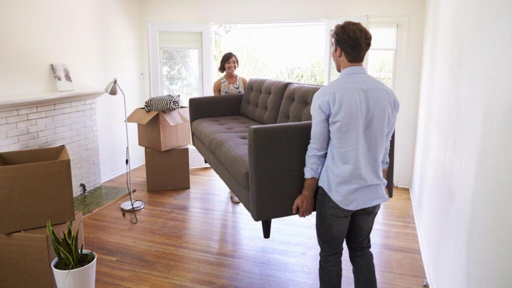 Picture of a Melbourne family moving into their home, holding a couch