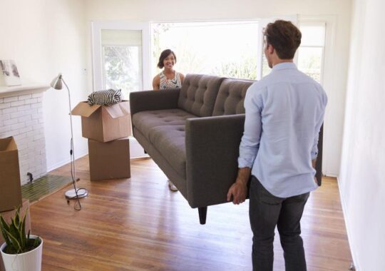 Picture of a Melbourne family moving into their home, holding a couch