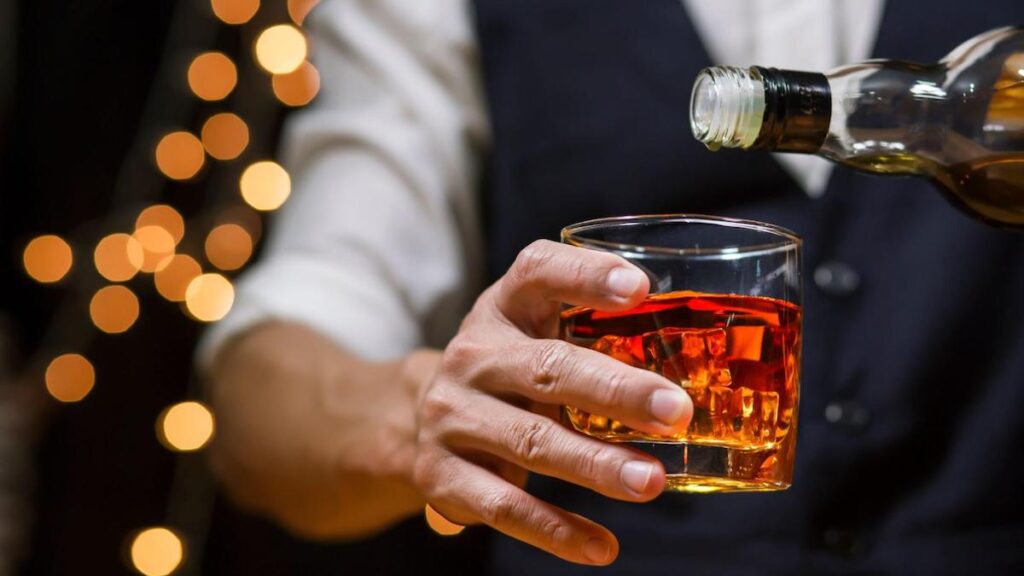 Picture of a man pouring whisky into a glass behind a bar at a Melbourne whisky bars