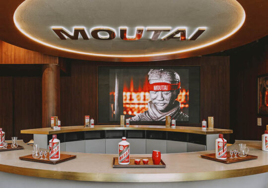Kweichow Moutai Melbourne store with eight table places and Kweichow Moutai infront of each seat and branding on the wall of the store