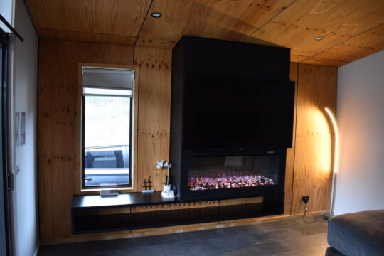 Living room accommodation at BIG4 Yarra Valley Park Lane Holiday Park, showing a artificial fire and window