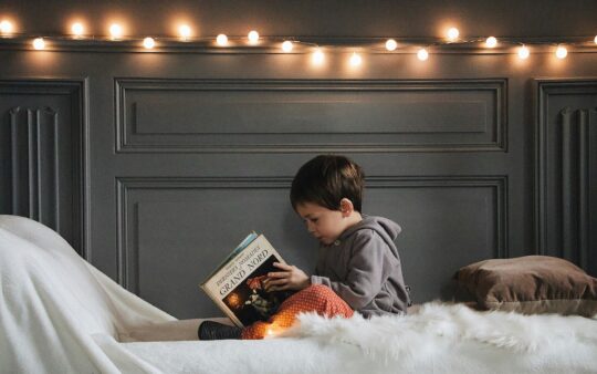 Picture of a boy reading in his bed with festoon lights after his toddler room reno