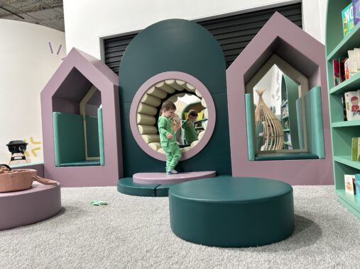 Child playing in the reading nook at Eden Play in Mill Park, surrounded by colourful play equipment