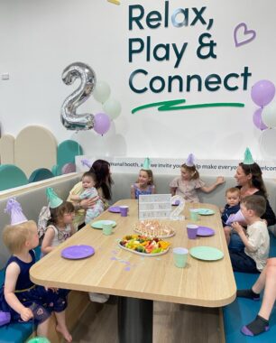 Picture of a kids party at Eden Play Mill Park, sitting around a table with party hats on and eating food.